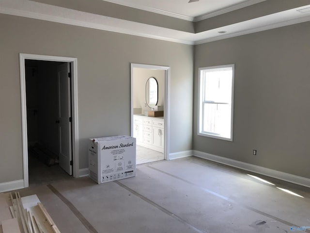 unfurnished bedroom with a tray ceiling, connected bathroom, and crown molding