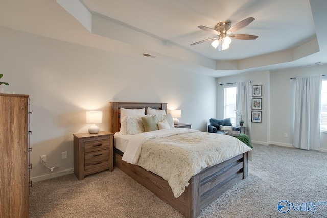 carpeted bedroom featuring ceiling fan and a tray ceiling