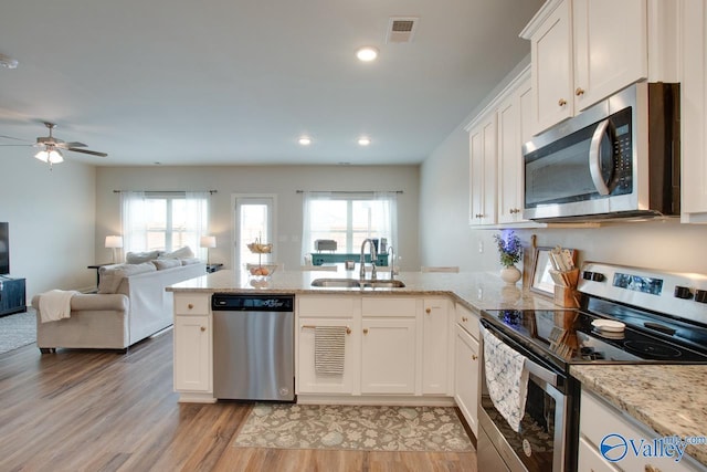 kitchen with stainless steel appliances, white cabinetry, sink, and kitchen peninsula