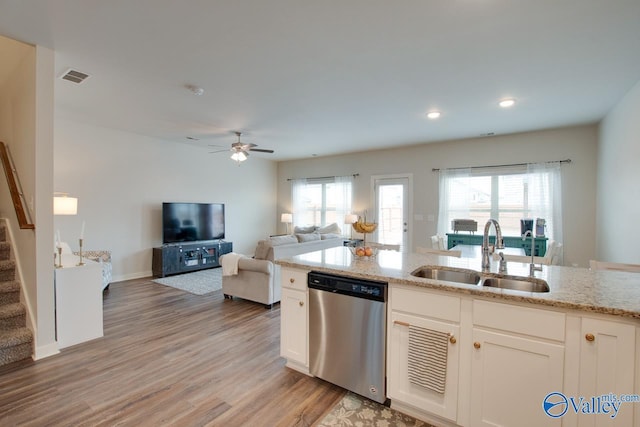 kitchen with light stone counters, stainless steel dishwasher, sink, and white cabinets