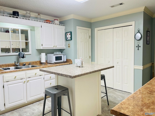 kitchen featuring white cabinetry, ornamental molding, a center island, and a kitchen breakfast bar