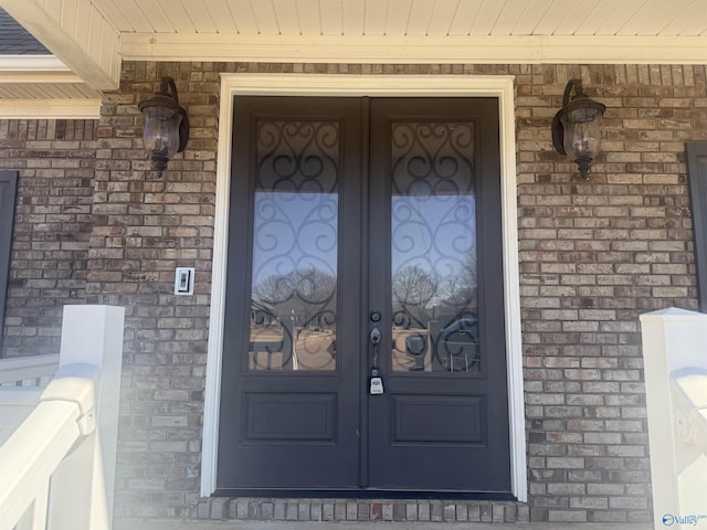 view of exterior entry featuring french doors and brick siding