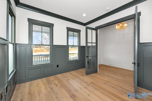 entryway featuring light wood finished floors, a decorative wall, a wainscoted wall, and recessed lighting