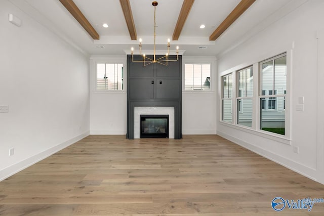 unfurnished living room featuring beam ceiling, a large fireplace, plenty of natural light, and wood finished floors