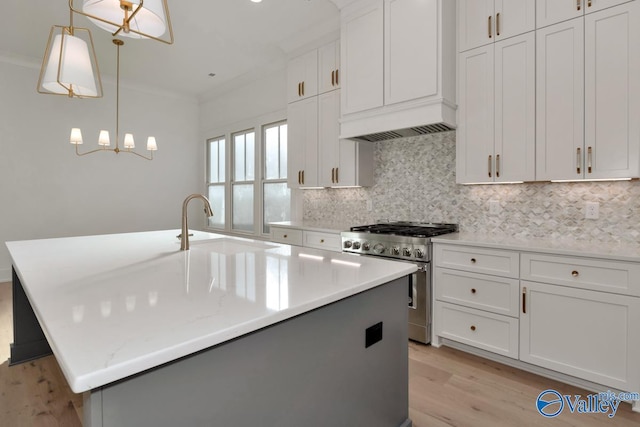 kitchen with white cabinetry, stainless steel range, a kitchen island with sink, and pendant lighting