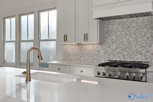 kitchen with light countertops, white cabinets, custom range hood, and decorative backsplash