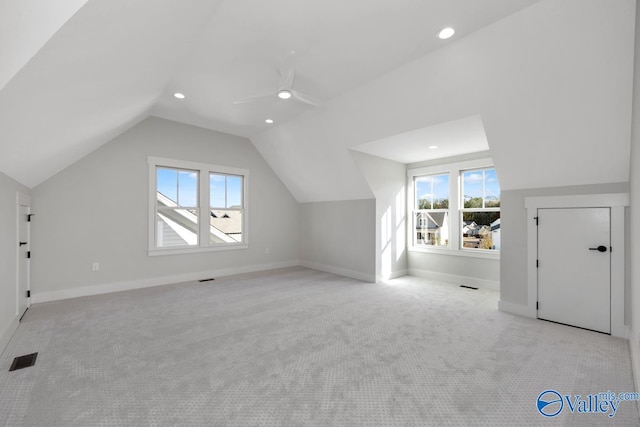 additional living space with light colored carpet, lofted ceiling, a healthy amount of sunlight, and visible vents