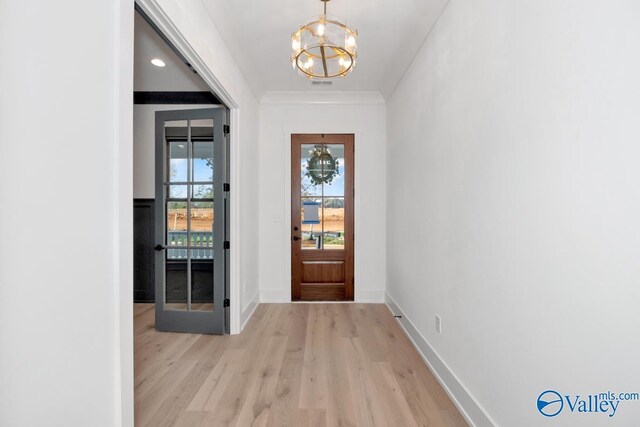 entrance foyer with baseboards, light wood finished floors, ornamental molding, and an inviting chandelier