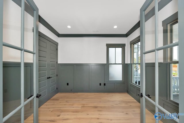 unfurnished room featuring light wood-style floors, a decorative wall, crown molding, and recessed lighting