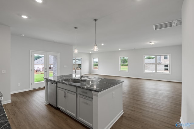 kitchen featuring stainless steel dishwasher, a healthy amount of sunlight, dark hardwood / wood-style flooring, and a kitchen island with sink