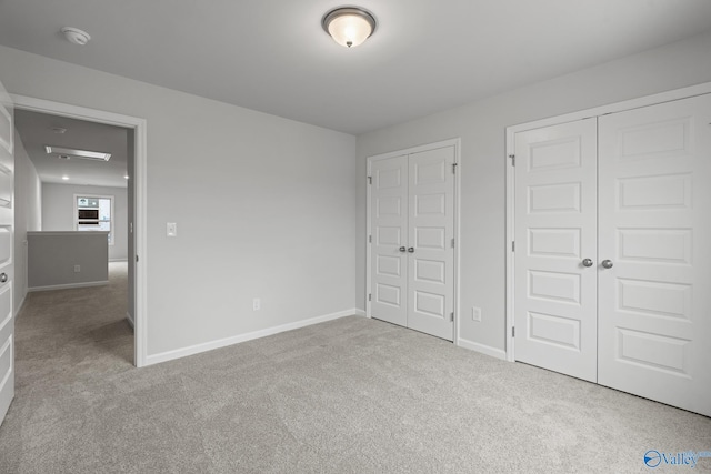 unfurnished bedroom with two closets and light colored carpet