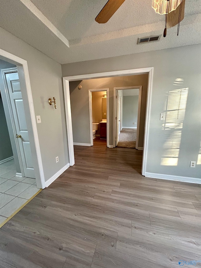 empty room with ceiling fan, light hardwood / wood-style flooring, and a textured ceiling