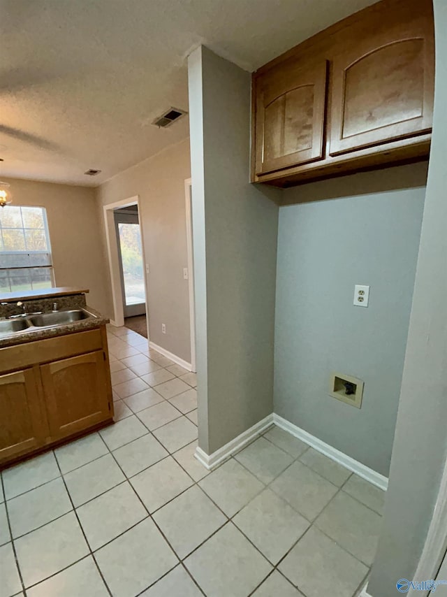 kitchen with light tile patterned flooring, sink, a notable chandelier, and a textured ceiling