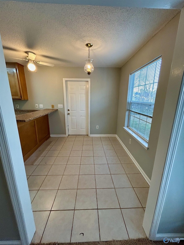 interior space featuring pendant lighting, a textured ceiling, ceiling fan, and light tile patterned flooring