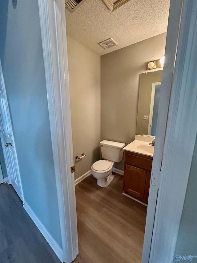 bathroom featuring wood-type flooring, vanity, a textured ceiling, and toilet