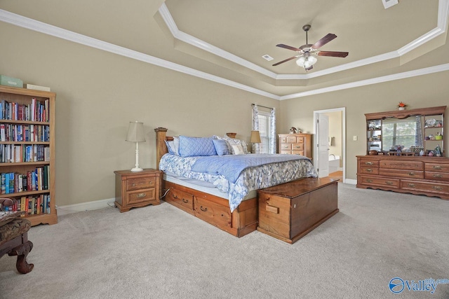 bedroom with ceiling fan, ensuite bathroom, a tray ceiling, ornamental molding, and light carpet