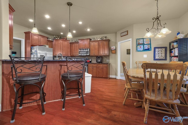 kitchen featuring pendant lighting, stainless steel appliances, a kitchen breakfast bar, dark hardwood / wood-style flooring, and kitchen peninsula