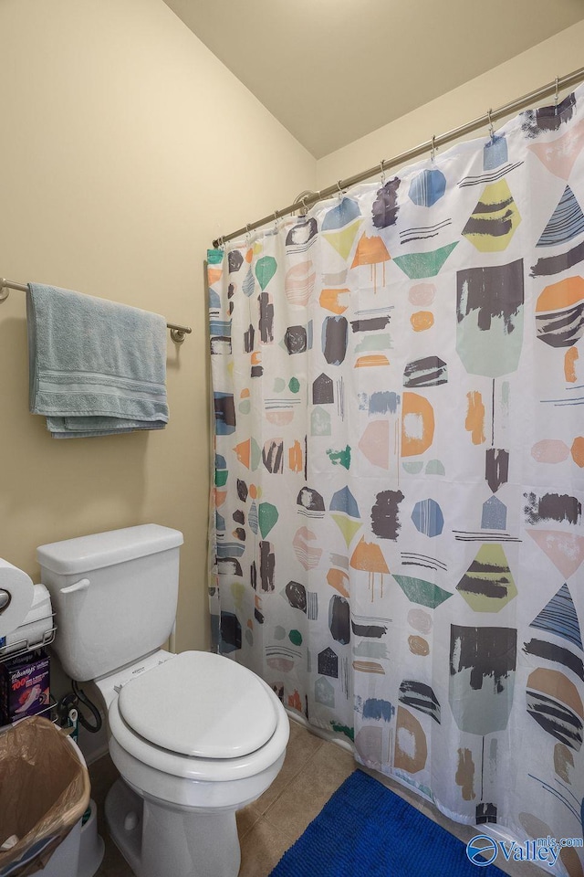 bathroom featuring tile patterned floors, toilet, and curtained shower