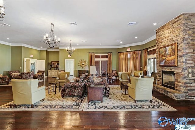 living room with hardwood / wood-style flooring, a fireplace, a chandelier, and crown molding