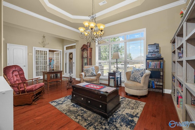 living area featuring crown molding, a tray ceiling, dark wood-type flooring, and a chandelier