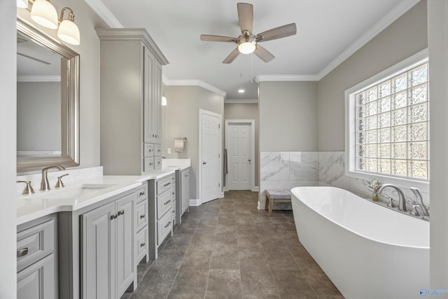 bathroom featuring ceiling fan, tile walls, vanity, a freestanding bath, and crown molding