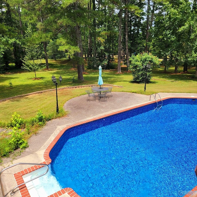 view of swimming pool featuring a lawn and a patio