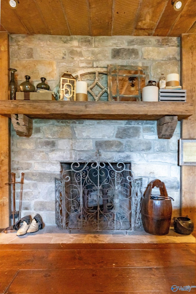 interior details with wooden ceiling, a stone fireplace, and wood finished floors