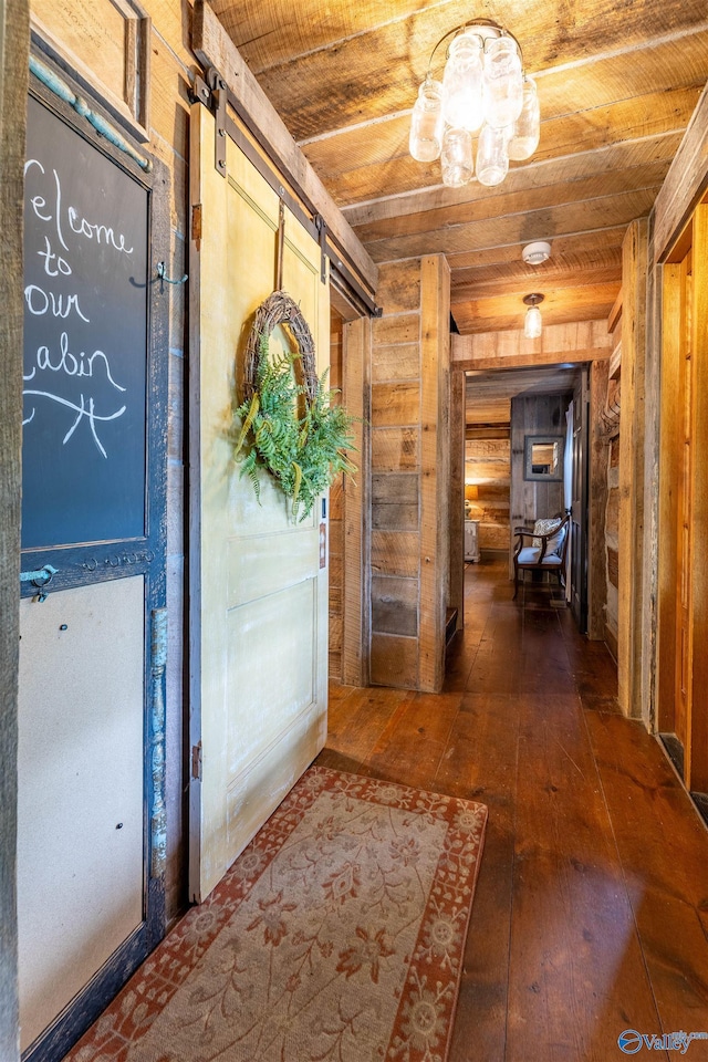 hallway featuring wooden walls, wood ceiling, and a barn door