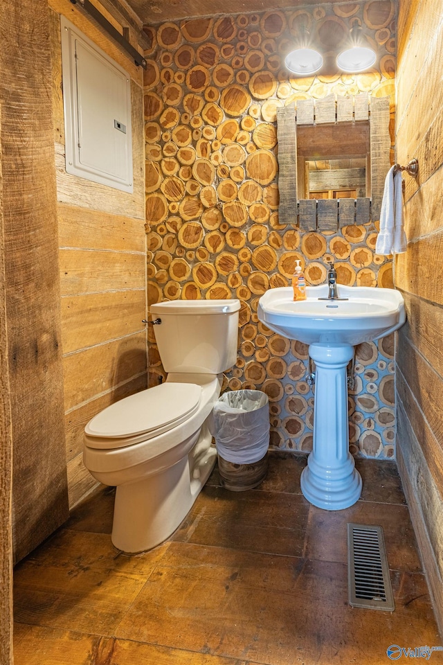 half bathroom featuring wood-type flooring, toilet, and visible vents