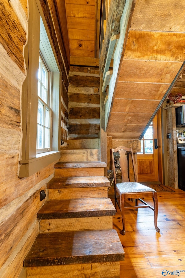 staircase with wood walls, wooden ceiling, vaulted ceiling, and hardwood / wood-style floors