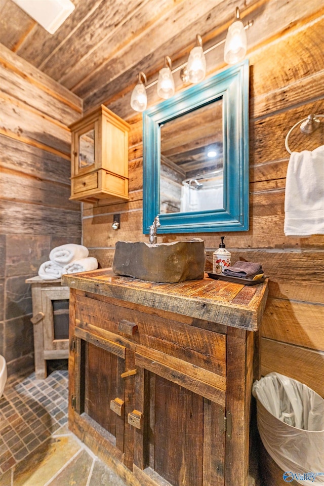 bathroom featuring vanity, wood walls, stone finish floor, and wooden ceiling