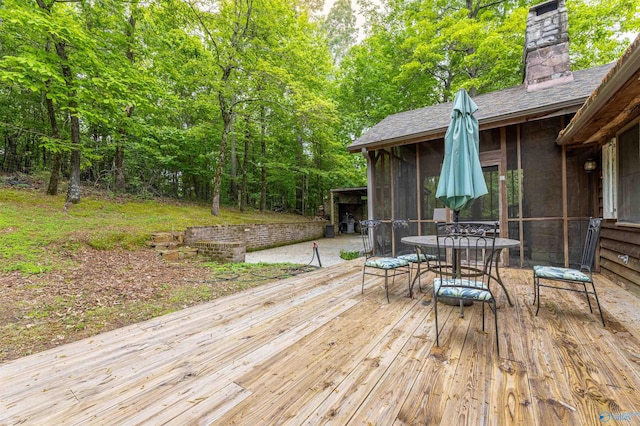 deck featuring a view of trees and outdoor dining space