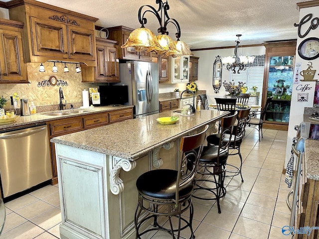 kitchen with light tile patterned floors, a textured ceiling, appliances with stainless steel finishes, and brown cabinets