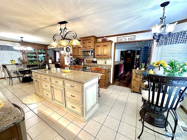 kitchen featuring an inviting chandelier, light tile patterned floors, stainless steel appliances, and a textured ceiling