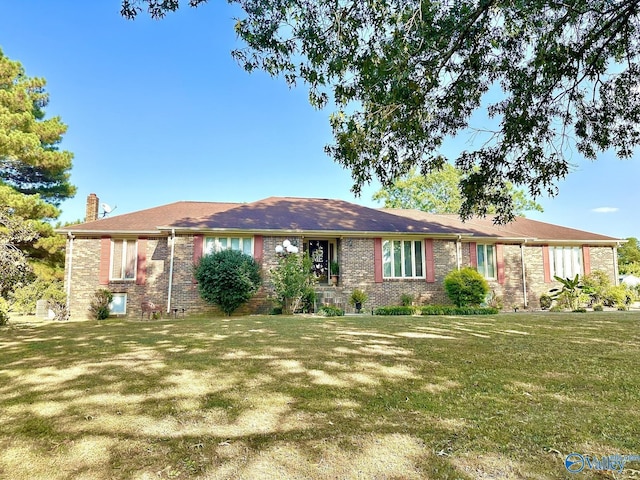 ranch-style house featuring a front yard, brick siding, and a chimney