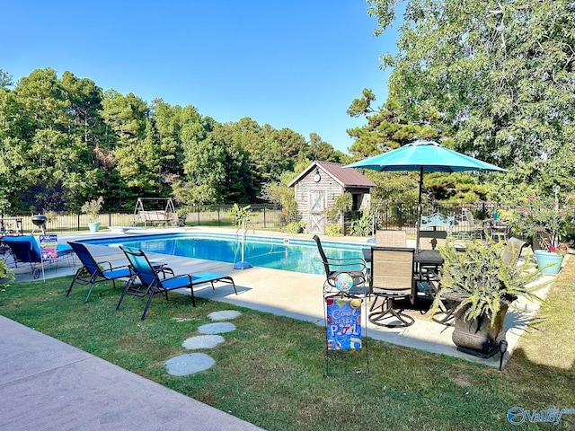 view of swimming pool featuring an outdoor structure, a fenced in pool, a yard, and fence