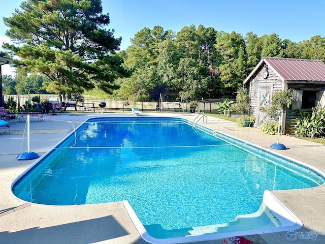 view of pool with an outdoor structure, a fenced in pool, a storage unit, and fence