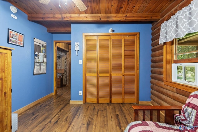 bedroom featuring dark wood-type flooring, beamed ceiling, rustic walls, and wooden ceiling