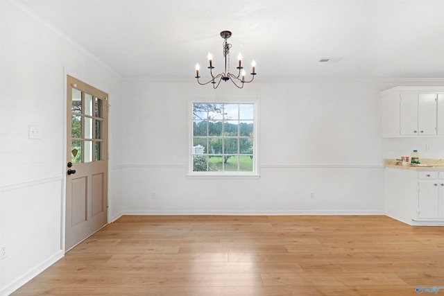 unfurnished dining area with light hardwood / wood-style flooring, an inviting chandelier, and ornamental molding