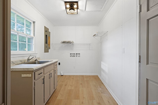 clothes washing area with light wood-type flooring, a textured ceiling, sink, ornamental molding, and hookup for a washing machine