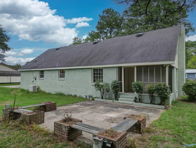 rear view of house featuring a patio, a sunroom, a lawn, and central air condition unit