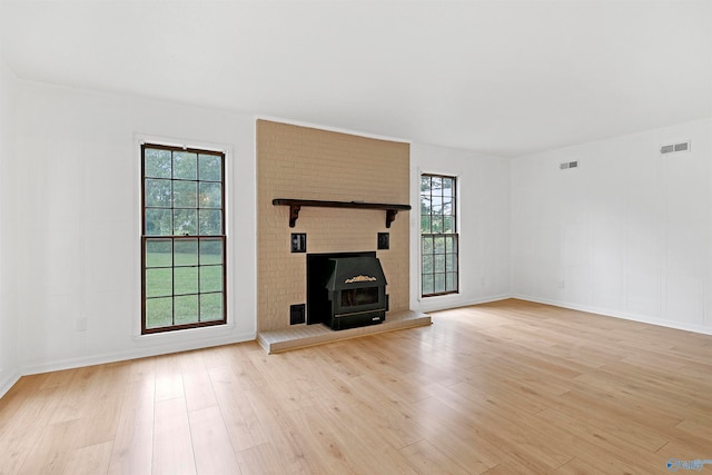 unfurnished living room featuring a fireplace, light hardwood / wood-style floors, and a healthy amount of sunlight