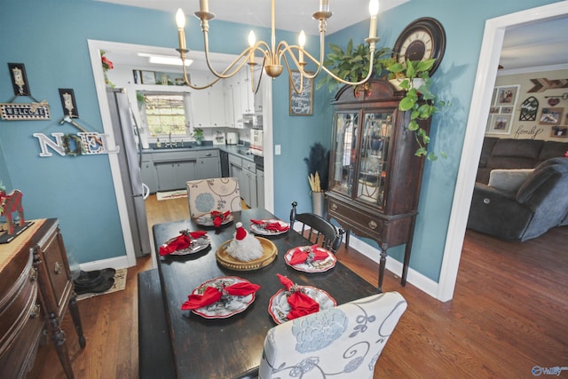 dining room with crown molding, sink, dark wood-type flooring, and a chandelier