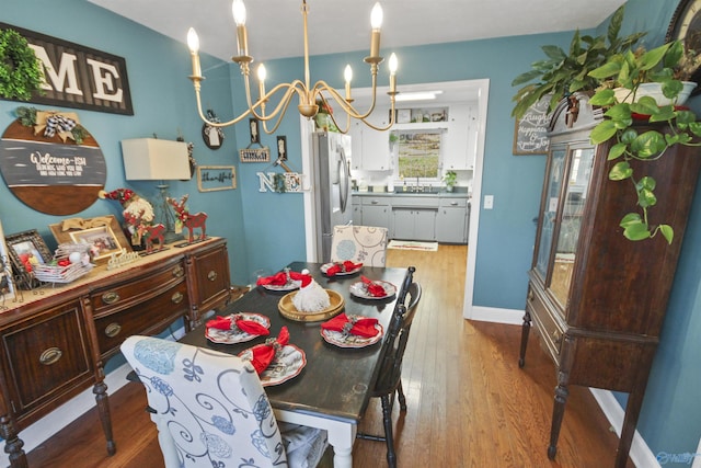 dining area featuring light hardwood / wood-style floors, sink, and an inviting chandelier