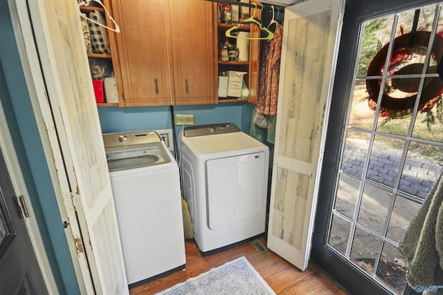 washroom featuring cabinets, light hardwood / wood-style floors, and washer and clothes dryer