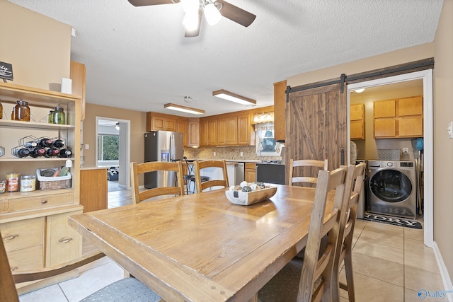 tiled dining room featuring washer / dryer, a textured ceiling, a barn door, and ceiling fan