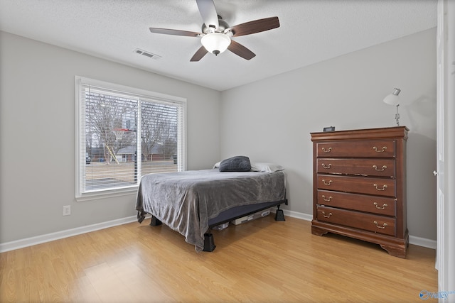 bedroom featuring ceiling fan, light hardwood / wood-style flooring, and a textured ceiling