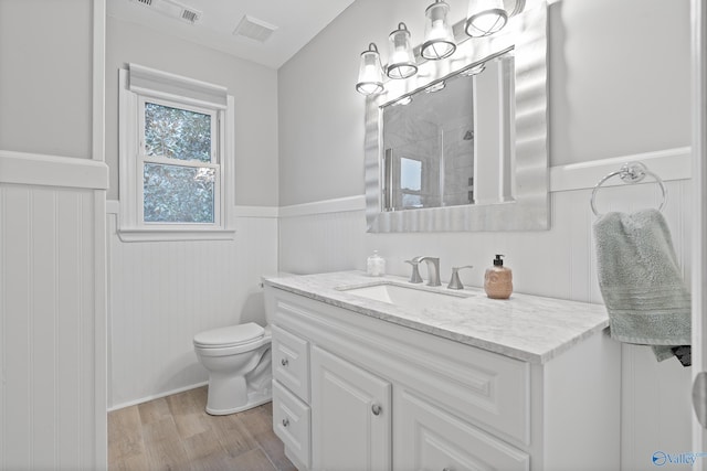 bathroom with hardwood / wood-style flooring, vanity, a shower, and toilet