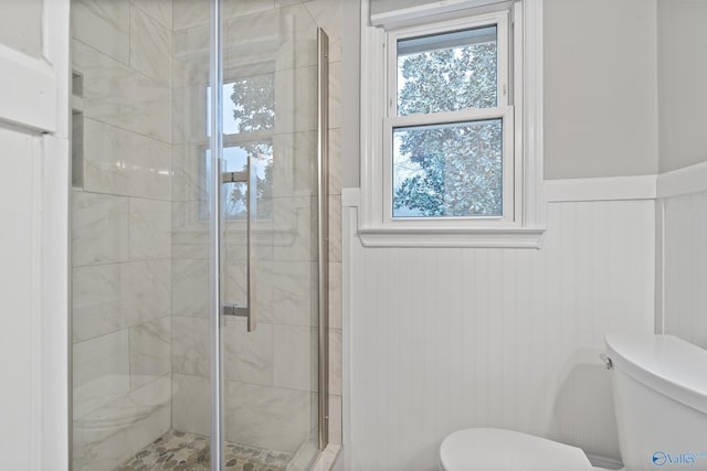 bathroom featuring a shower with shower door and toilet