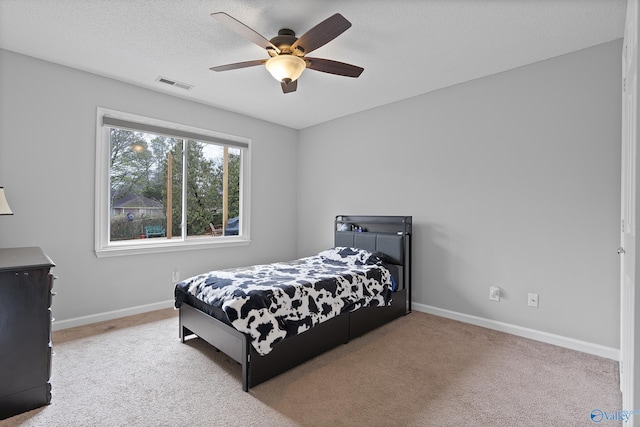 carpeted bedroom with ceiling fan and a textured ceiling